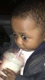 A black kid drinking a smoothie with a straw, doing big eyes